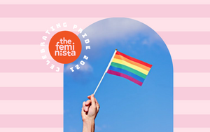 Hand holding a rainbow Pride flag up in the air on a blue sky and pink background with The Feminista logo and the text 