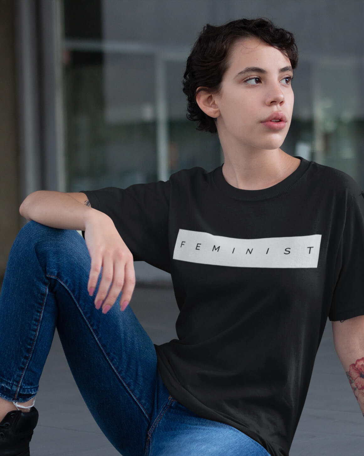 Seated woman in graphic t-shirt that reads: feminist
