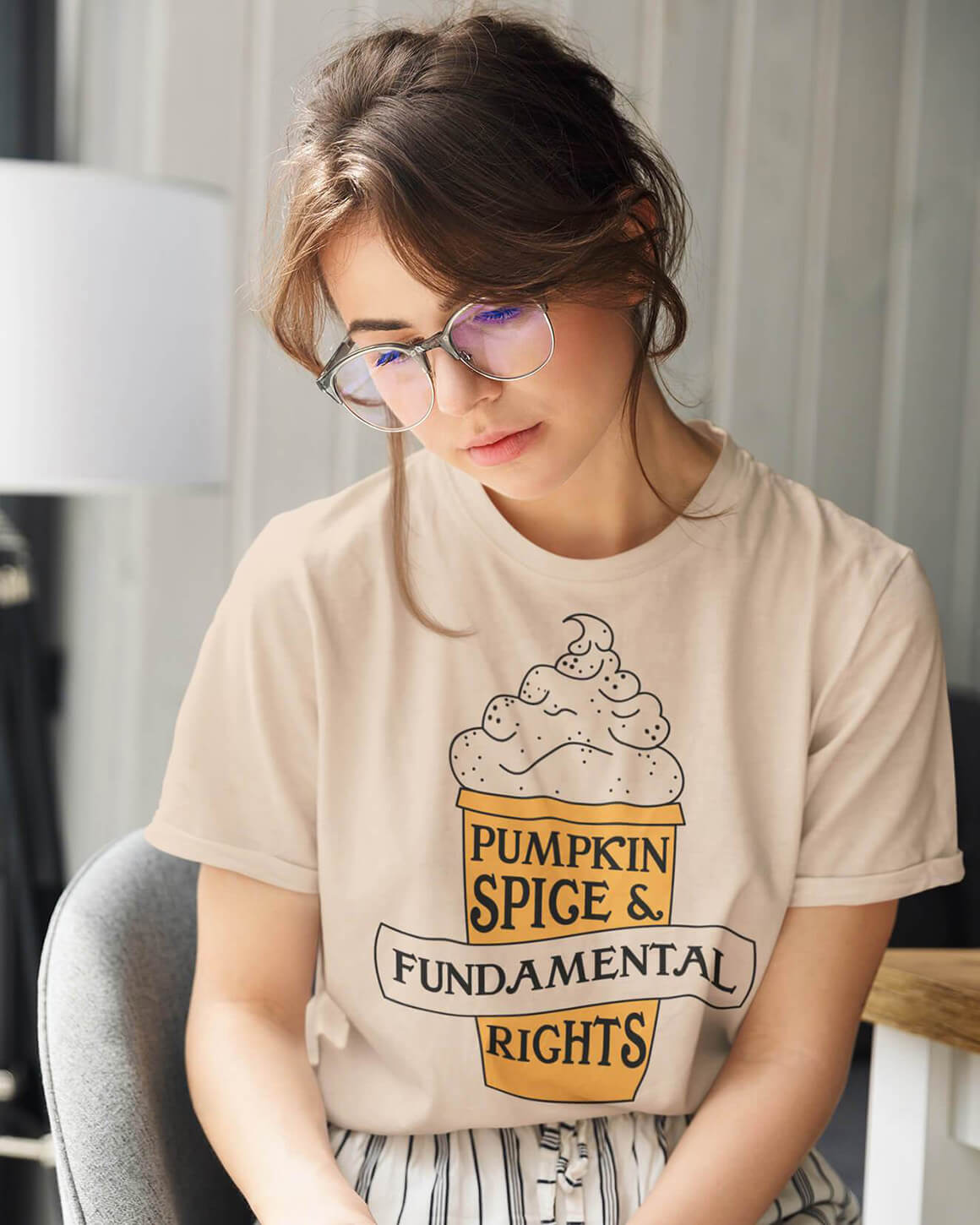 Girl with glasses wearing tan pumpkin spice and fundamental rights t shirt